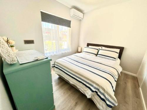 a bedroom with a bed with a green cabinet and a window at Ocean Reef Retreat in Perth