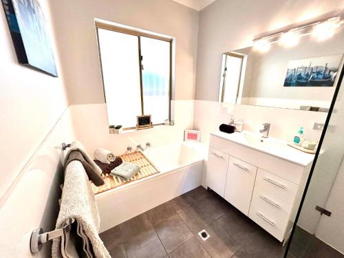 a bathroom with a tub and a sink and a mirror at Ocean Reef Retreat in Perth