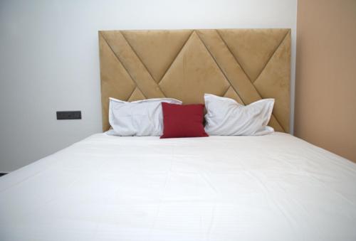 a white bed with a red pillow on it at French Villa in Dankotuwa