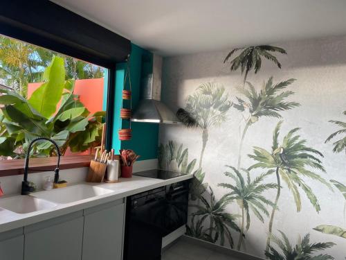 a kitchen with palm trees mural on the wall at Villa Exotiqua Sunset in La Saline les Bains