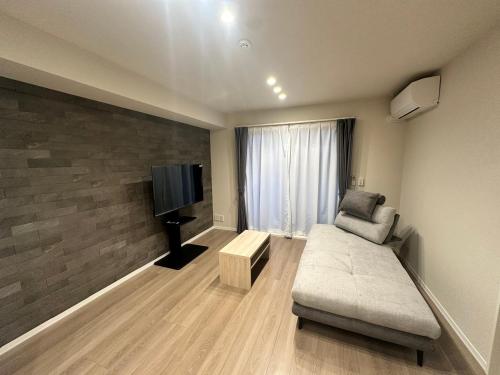 a living room with a couch and a flat screen tv at Opt熊本光の森 in Kikuyo