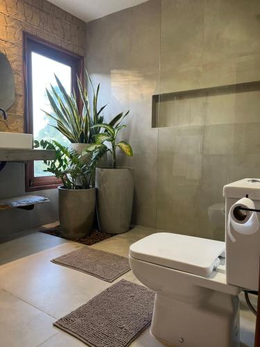 a bathroom with a toilet and two potted plants at Vila Refúgio in Aracati