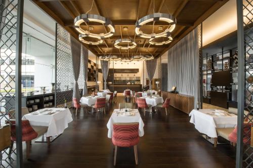 a restaurant with white tables and chairs and a chandelier at Grand Fiesta Americana Puebla Angelópolis in Puebla