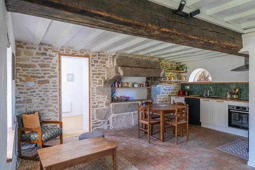 a kitchen with a table and chairs and a brick wall at La Garencière - La Petite Maison in Champfleur