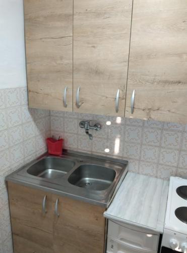 a kitchen with a stainless steel sink and wooden cabinets at Apartman Marinamar in Utjeha