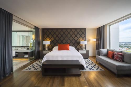 a bedroom with a bed and a couch at Grand Fiesta Americana Puebla Angelópolis in Puebla