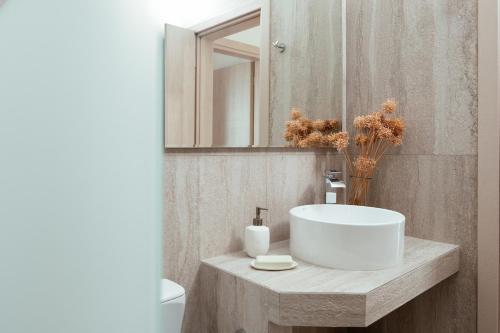 a bathroom with a white sink and a mirror at Kyma Paros Sea View Luxe Suite in Paros National Airport