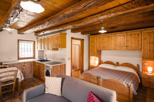a bedroom with a bed and a kitchen with wooden cabinets at Albergo Diffuso Ravascletto in Ravascletto