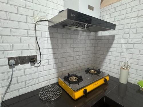 a stove in a kitchen with a white brick wall at ff HILLTOP VIEW in Kampong Kundassan