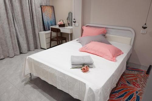 a bedroom with a large white bed with pink pillows at Nadi Ease Stay Near McDonalds in Nadi