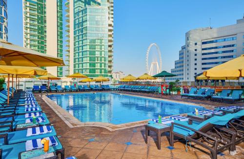 a swimming pool with blue tables and chairs and buildings at Ramada Hotel, Suites and Apartments by Wyndham Dubai JBR in Dubai