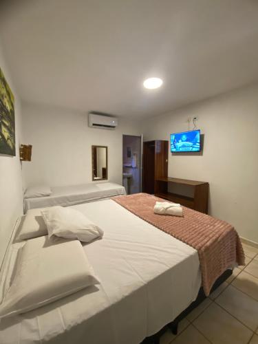 a bedroom with two beds and a tv on the wall at Pousada Rota Beach in Porto De Galinhas