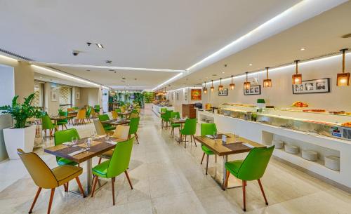 a restaurant with wooden tables and green chairs at Ramada Hotel, Suites and Apartments by Wyndham Dubai JBR in Dubai