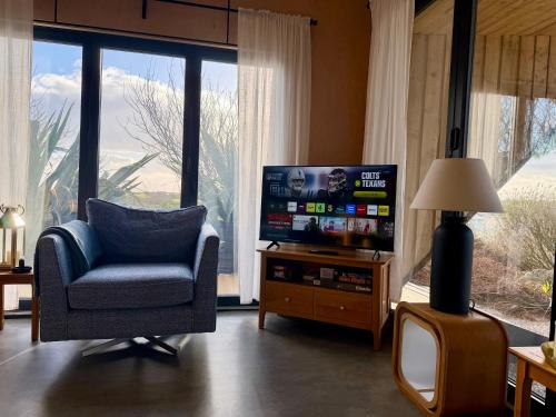 a living room with a chair and a flat screen tv at The Timber Lodge - Sennen Holiday Home in Sennen