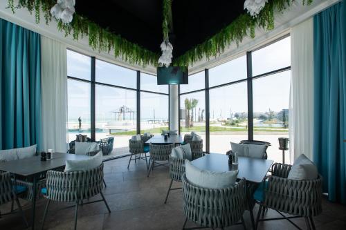 een restaurant met tafels en stoelen en grote ramen bij Caspi Mayr in Baku