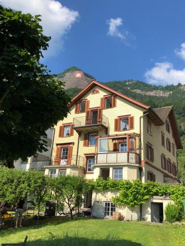 a large yellow building with a hill in the background at BnB Villa Kapellmatt - Seezugang, Bio-Frühstück, SUP am Rigi in Vitznau
