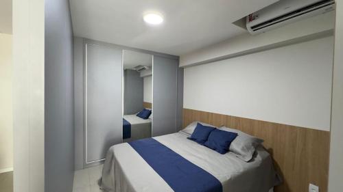 een slaapkamer met een bed met blauwe kussens en een spiegel bij Sea View Apartment in Aracaju in Aracaju