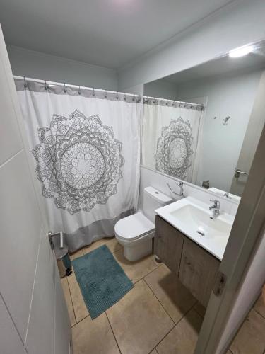 a bathroom with a toilet and a sink and a shower curtain at Comfort, Safety, and Connectivity in Chillán