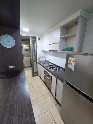 a kitchen with white cabinets and a stove top oven at Comfort, Safety, and Connectivity in Chillán