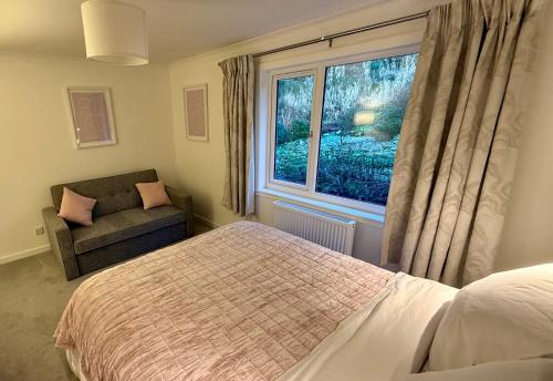 a bedroom with a bed and a window and a chair at Oaktree Cottage, overlooking Loch Fyne in Cairndow