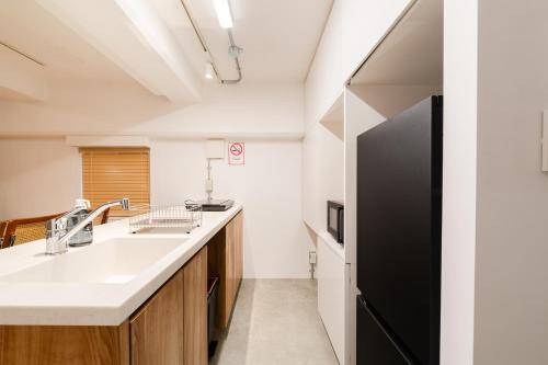 a kitchen with a sink and a black refrigerator at Shibuya Beatles house 10min walk from Shibuya Station in Tokyo