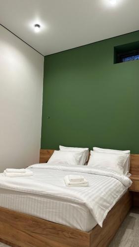 a bed with white sheets and a green wall at House In Dilijan in Dilijan