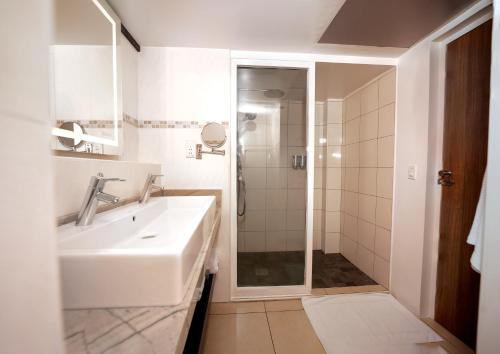 ein weißes Badezimmer mit Waschbecken und Dusche in der Unterkunft Royal Torarica in Paramaribo