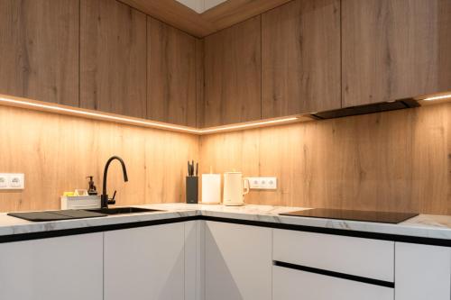 a kitchen with white cabinets and a sink at Apartament Zakrzówek - Chilloway in Krakow