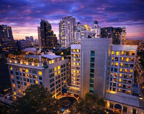 a city skyline at night with a tall building at Radisson Suites Bangkok Sukhumvit in Bangkok
