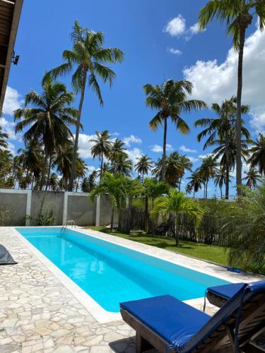 a swimming pool with palm trees in the background at Coco Ville SMG in São Miguel do Gostoso