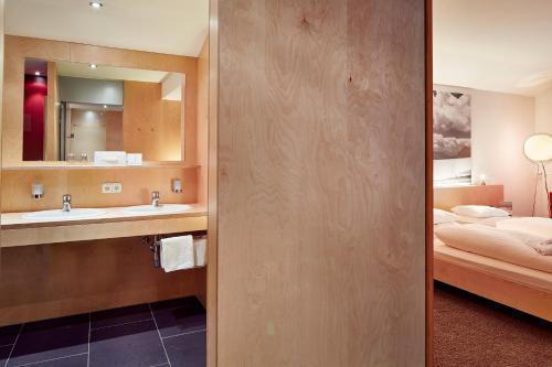 een badkamer met een wastafel en een bed in een kamer bij Pop-up Hostel - Loisach in Lermoos