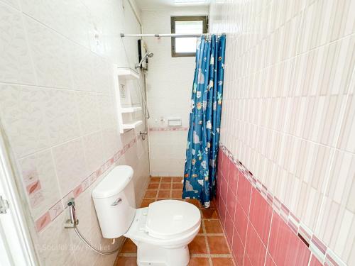 a bathroom with a toilet and a blue shower curtain at Soulful Stay Phuket -Distant Seaview and Mountain View Retreat, Patong in Patong Beach