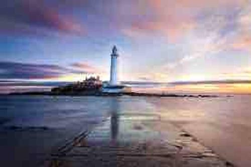 a lighthouse on a beach with a cloudy sky at Peaceful Whitley Bay Getaway with Shared Indoor Pool in Whitley Bay