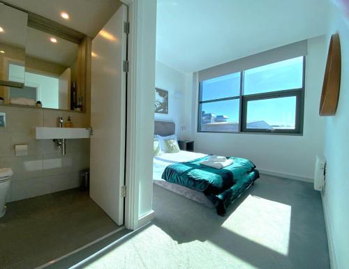a bedroom with a bed and a bathroom with a window at Modern 2-Bed Apartment in Blu Bracknell in Bracknell