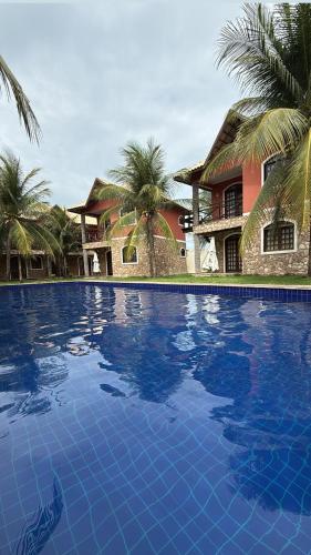 a large blue swimming pool in front of a house at Chalé em Condomínio com in Aracati