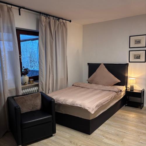 a bedroom with a bed and a chair and a window at Waldblick Glatt in Sulz am Neckar