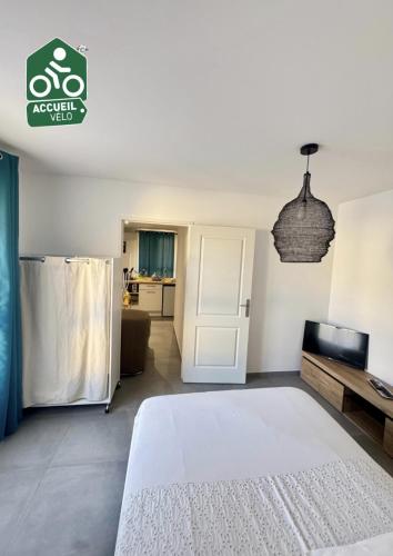 a bedroom with a white bed and a living room at Hébergement neuf, centre-ville de Morestel - Résidence Boyraz in Morestel