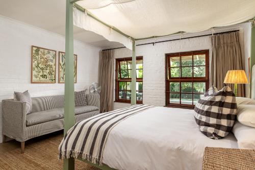 a bedroom with a canopy bed and a chair at Noordhoek Village Hotel in Noordhoek