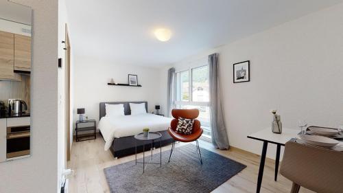 een slaapkamer met een bed, een tafel en een stoel bij Nonanteneuf appart hōtel Aigle - contactless check-in in Aigle