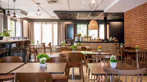 a restaurant with tables and chairs and a brick wall at Campanile Brive-La-Gaillarde Ouest in Brive-la-Gaillarde