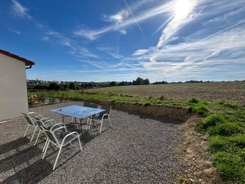 a table and chairs on a gravel patio next to a field at Paisible MAISON familiale - 4 Chambres - 2 SDB - terrasse et jardin - parking privé - Limoges in Limoges