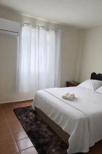 a bedroom with a white bed and a window at Kit net em Penedo l perto do centro turístico in Itatiaia