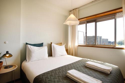 a bedroom with a bed with white pillows and a window at Casa Guilhermina, Sunny Studio with Balcony in Porto