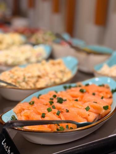 een tafel vol borden met eten, waaronder wortels bij Hotel Schultheiss Hameln in Hameln