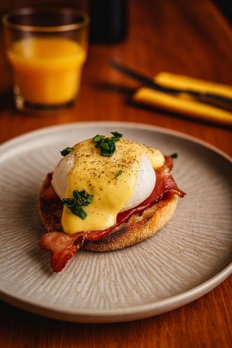 een ontbijtsandwich met een ei en spek op een bord bij Hotel Schultheiss Hameln in Hameln