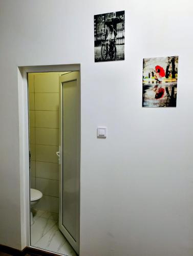 a bathroom with a toilet and two pictures on the wall at GuestHouse5 KARMA369 in Plovdiv