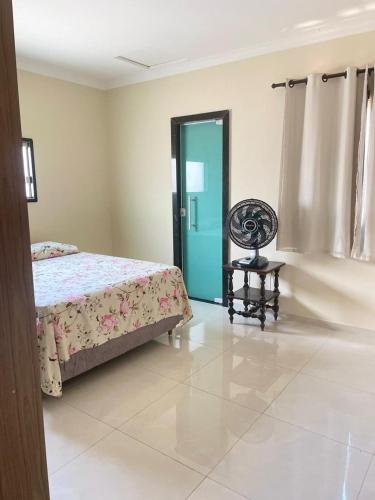 a bedroom with a bed and a chair and a door at Casa temporada em Perocão in Guarapari