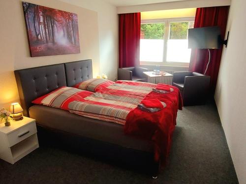 een slaapkamer met een bed met een rood dekbed bij Hotel Georgenhöhe Wildemann in Wildemann
