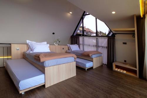 zwei Betten in einem Zimmer mit großem Fenster in der Unterkunft Northpine Cottages in Tegalharendong