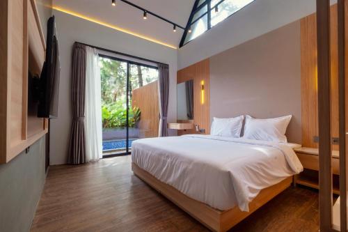 ein Schlafzimmer mit einem großen Bett und einem großen Fenster in der Unterkunft Northpine Cottages in Tegalharendong